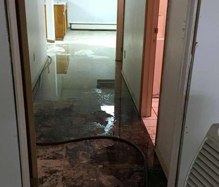 Sewage & water on hallway floor, partially dammed up to prevent spreading
